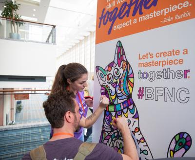 Two people coloring together on a sign at the conference